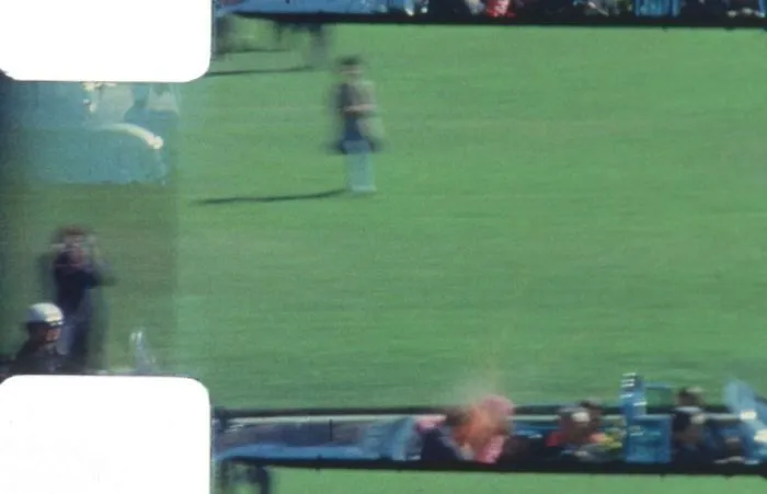 Iconic historical photo capturing a blurred moment with a grassy field, people, and a vehicle in motion.