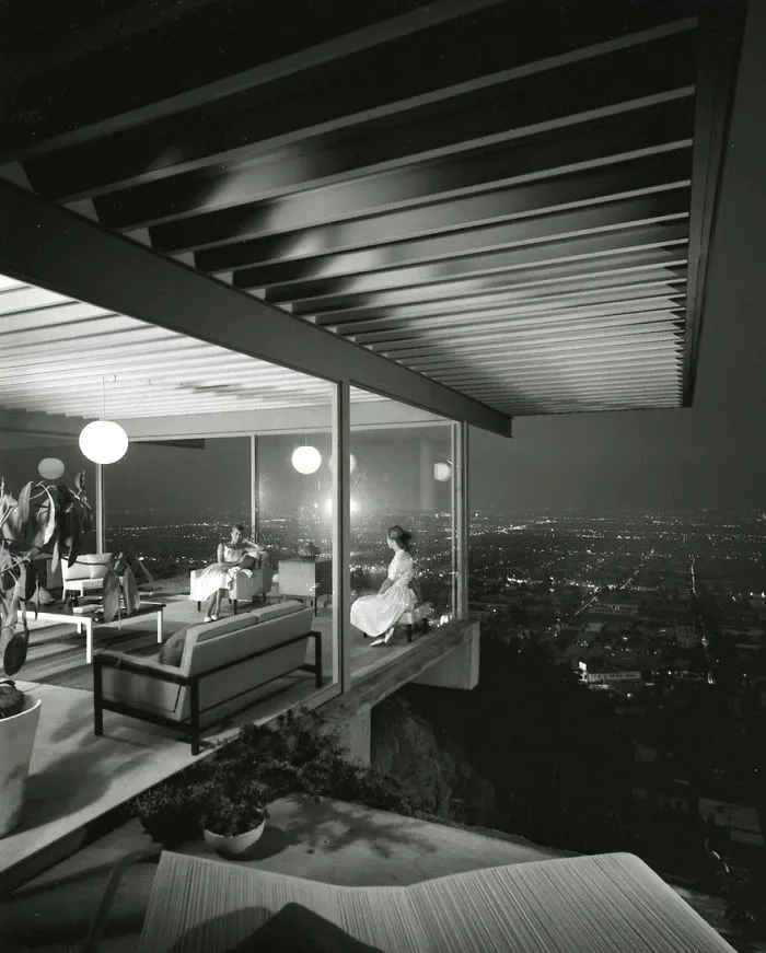 Modern home with a glass wall offers a panoramic city view at night, featured in famous historical photos.