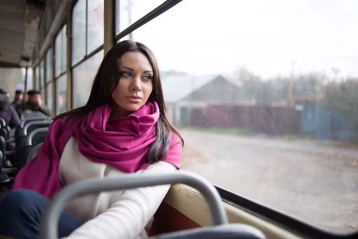 Woman in pink scarf gazing out a bus window, illustrating the truth behind beautiful photos pre-Photoshop.
