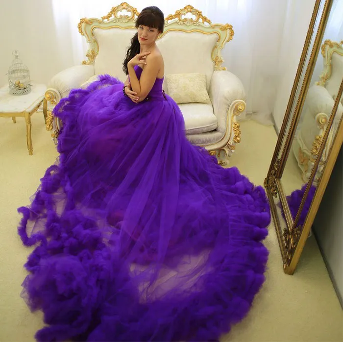 Woman in elegant purple gown on ornate sofa, showcasing beautiful photos, with reflection in the mirror.