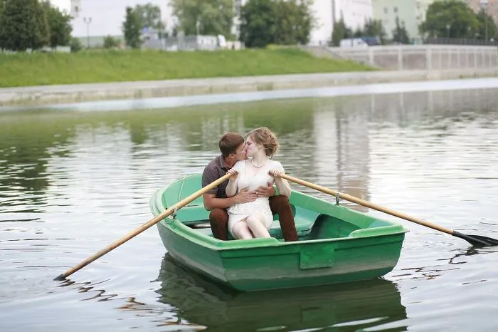 A couple in a boat on a calm lake, capturing a candid moment, revealing the truth behind beautiful photos.