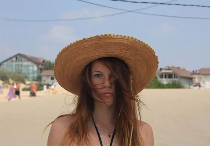 Woman on beach with straw hat, revealing the truth behind beautiful photos before Photoshop.