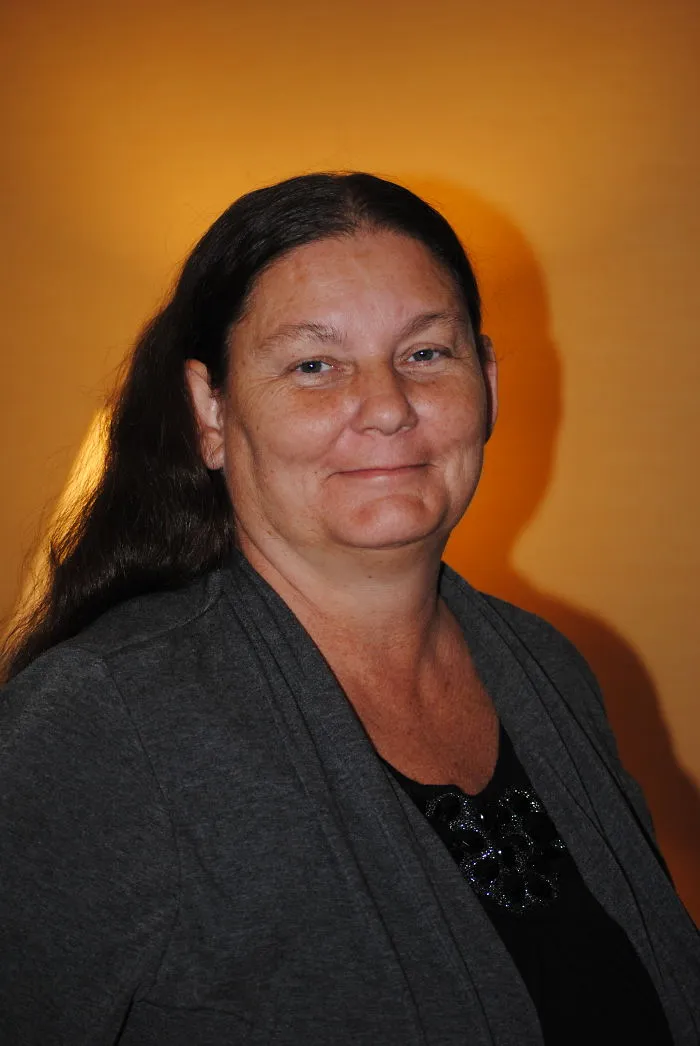 Middle-aged woman with long dark hair smiling gently, illustrating changes in health and appearance after stopping drinking.