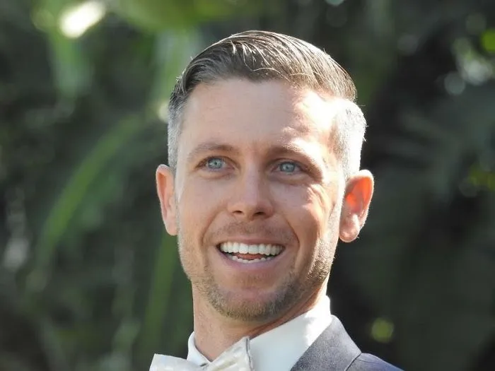 Smiling man in formal attire outdoors with clear skin and bright eyes, illustrating effects of stopping drinking.