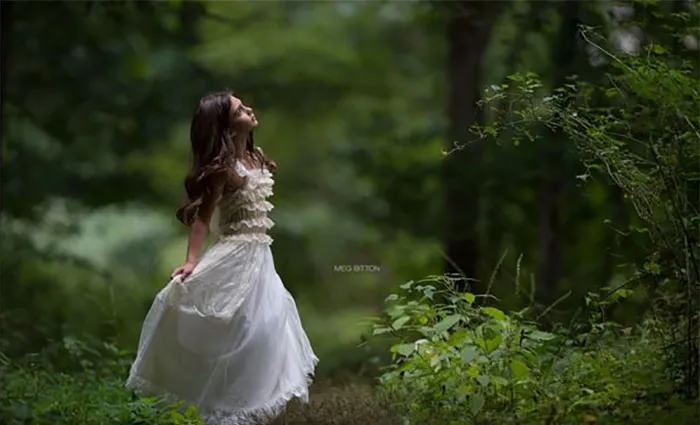 Woman in a white dress surrounded by a lush forest, demonstrating the impact of Photoshop on beautiful photos.