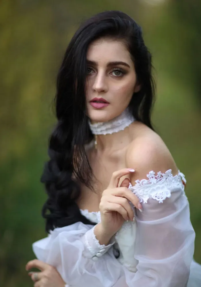 Woman in white lace dress posing outdoors, showcasing before and after Photoshop effects on beautiful photos.