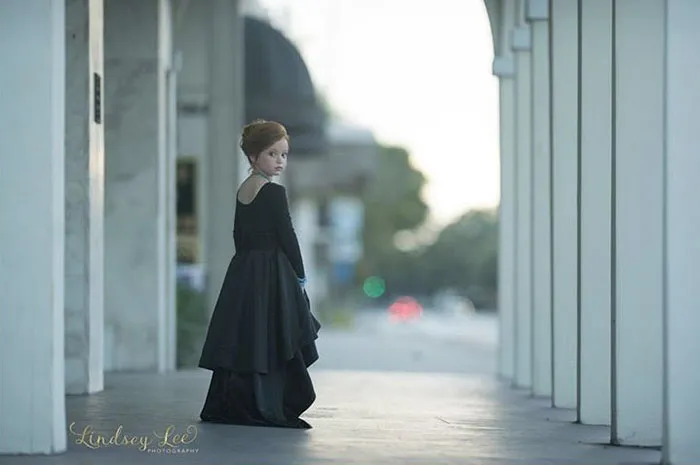 A woman in a long dark dress standing under archways, illustrating the impact of Photoshop on beautiful photos.