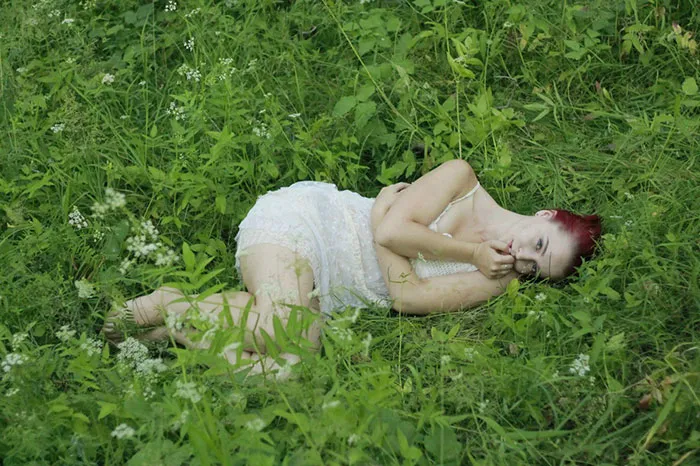 Woman lying in grass before Photoshop, revealing the truth behind beautiful photos.