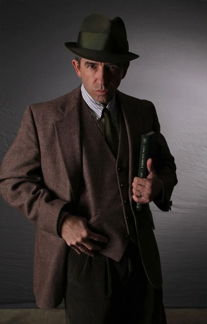 Man in a vintage suit and hat holding a book, showcasing the truth behind beautiful photos with Photoshop.