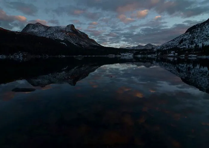 A serene mountain landscape reflecting on a lake at dusk, showcasing natural beauty before Photoshop enhancements.