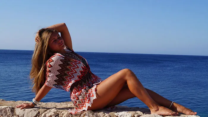 Woman posing by the sea, showcasing before and after Photoshop transformation.
