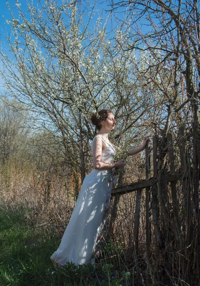 Woman in white dress in nature scene, framed by fence and trees; illustrating photo truth before Photoshop.