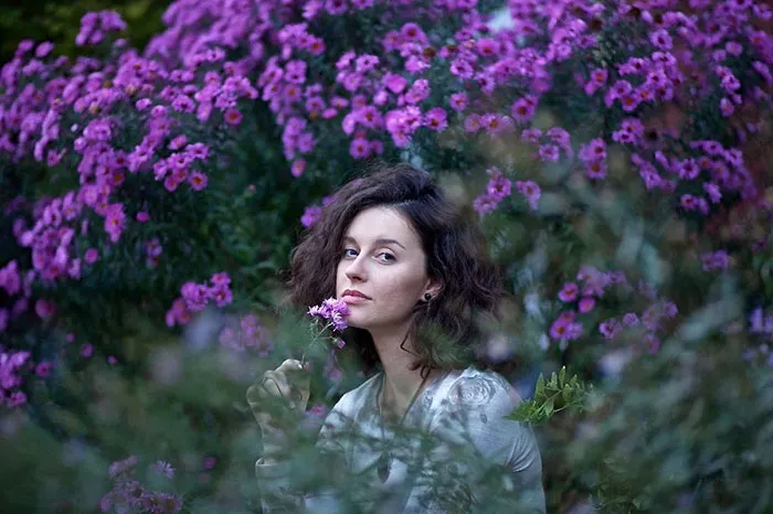 Woman in a garden with purple flowers, highlighting natural beauty before Photoshop editing.