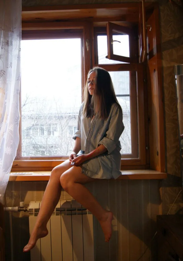 A woman sits on a windowsill, illustrating the truth behind beautiful photos before Photoshop editing.