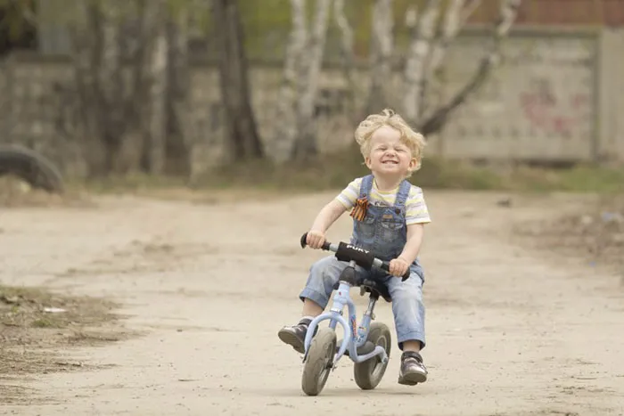 Child riding a small blue bike on a dirt path, showcasing the truth behind beautiful photos.
