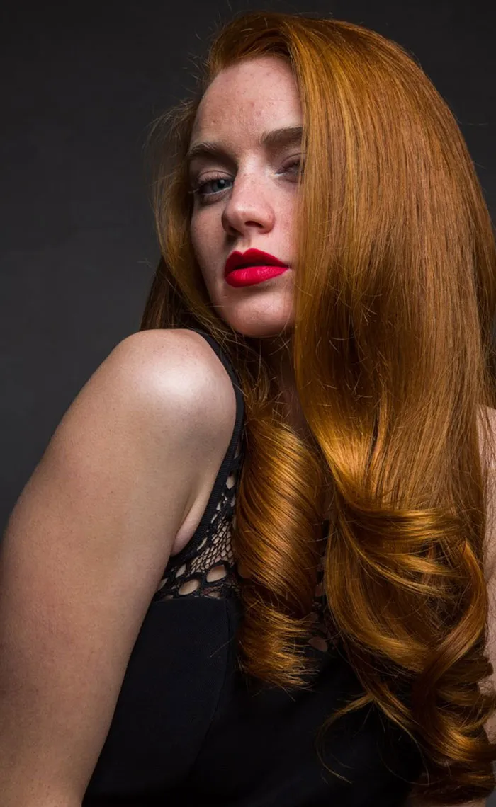 Red-haired woman in dramatic lighting showcasing beauty before Photoshop.