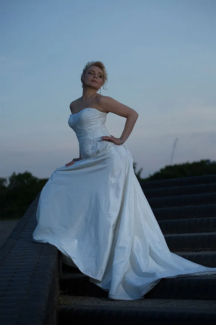 Woman in a white dress posing on stairs, highlighting the truth behind beautiful photos before Photoshop.