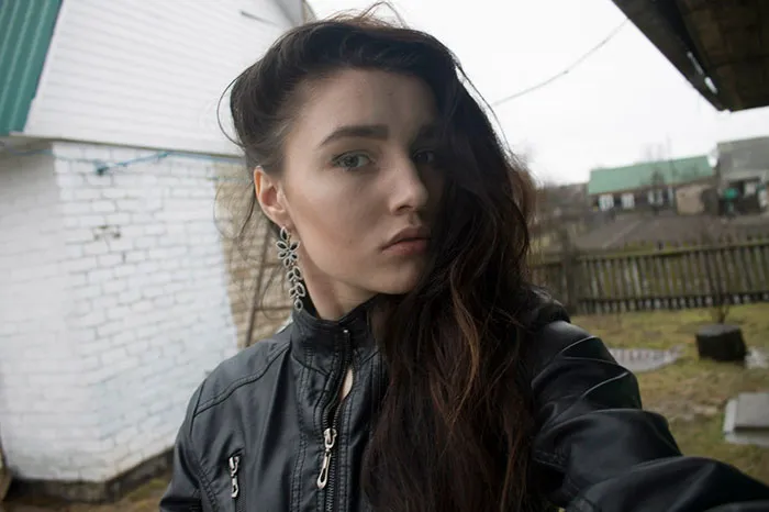 Woman in a black jacket outdoors with an unedited, natural appearance before Photoshop.