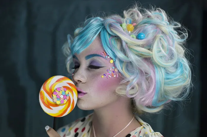 Woman with colorful makeup and pastel hair, holding a lollipop; showcases before and after Photoshop transformation.