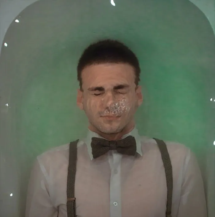 Man in water with distortion, eyes closed and wearing bow tie, showing Photoshop editing effects.