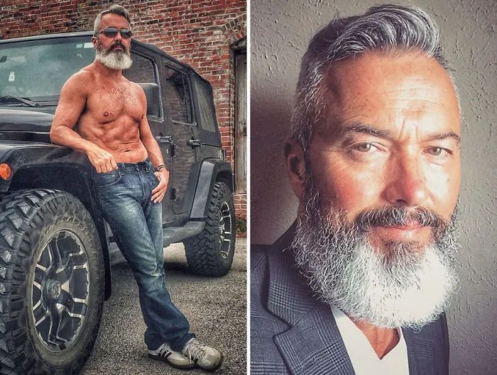 Handsome older man with a gray beard, posing by a black jeep and in a suit, redefining the concept of aging.