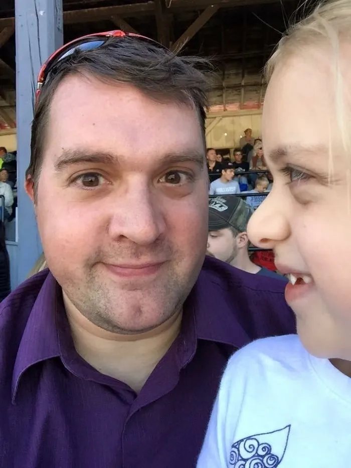 Man smiling with a young child at an outdoor event, illustrating before-and-after pics showing what happens when you stop drinking.