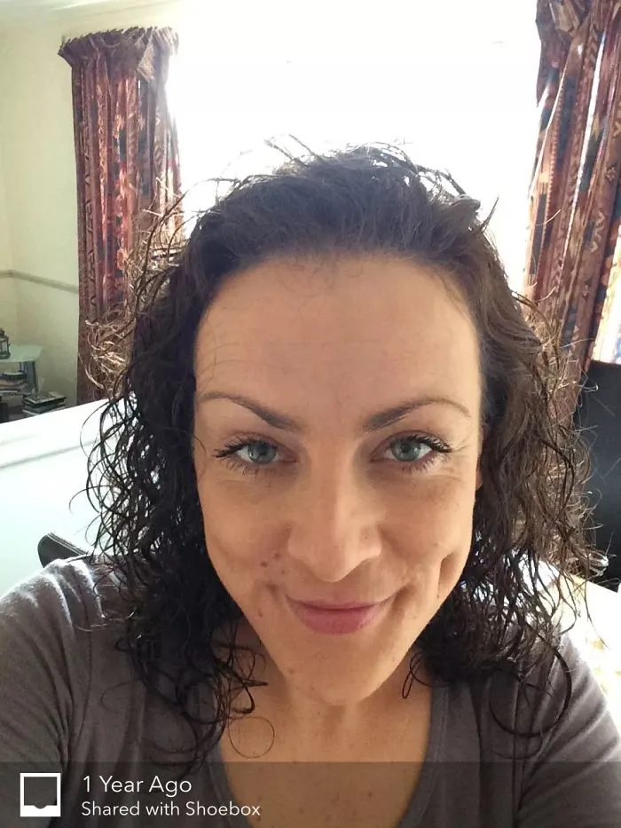 Close-up of a woman smiling with curly hair showing a healthy glow in before-and-after pics of stopping drinking.