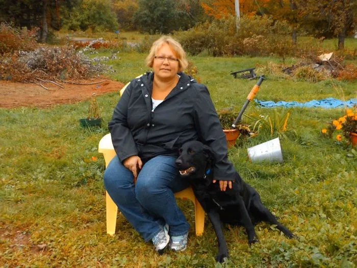 Woman sitting outdoors in a garden with a black dog, illustrating positive changes from before-and-after pics when stopping drinking.