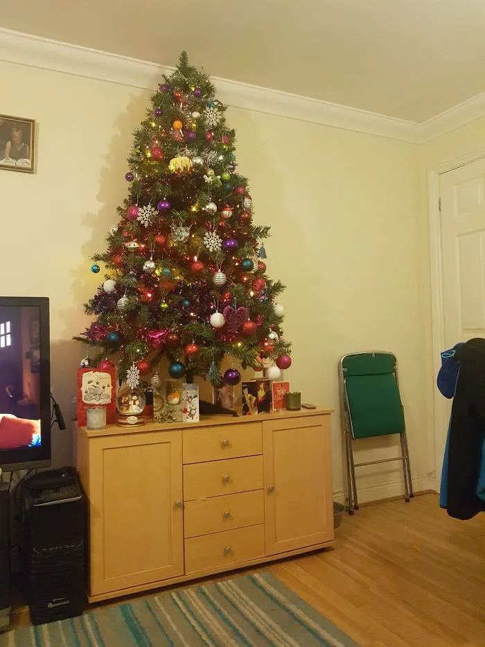 Christmas tree atop a cabinet, keeping decorations safe from cats and dogs.