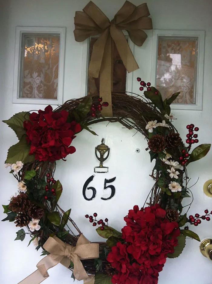 Wreath on door with hidden face peeking through window, creating a freaky surprise.