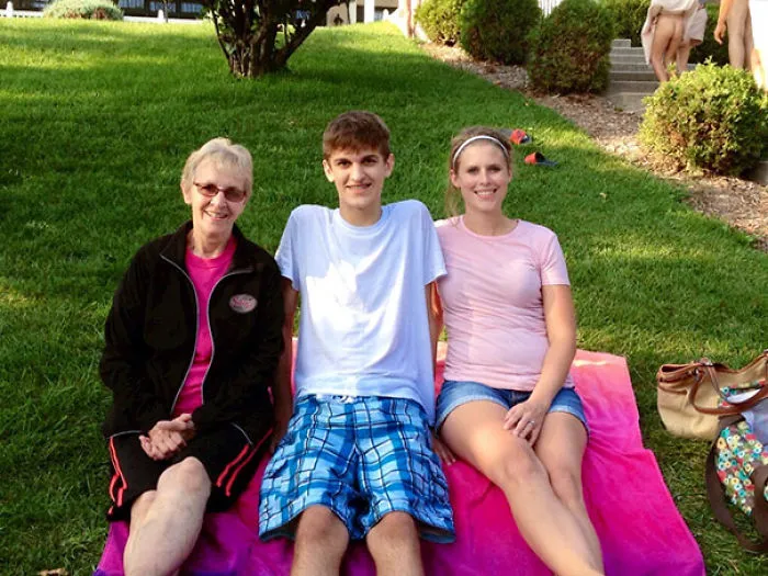 Family sitting on a picnic blanket in a garden, revealing a hidden figure in the background that might surprise you.