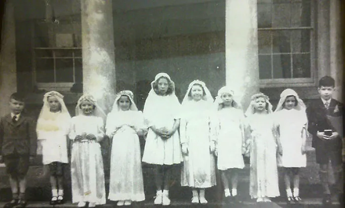 Children posing in front of a building, with a surprising detail you'll notice when you see it.