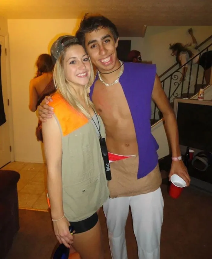 Two people posing happily at a party with a surprising detail in the background.