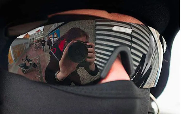 Reflection of a person with a camera in sunglasses, creating an eerie effect when you see it.