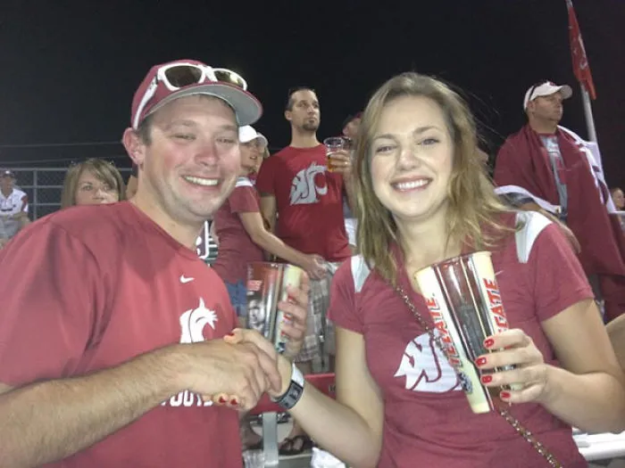 Couple shaking hands at a game, fans in matching shirts; surprising detail captures attention when you see it.