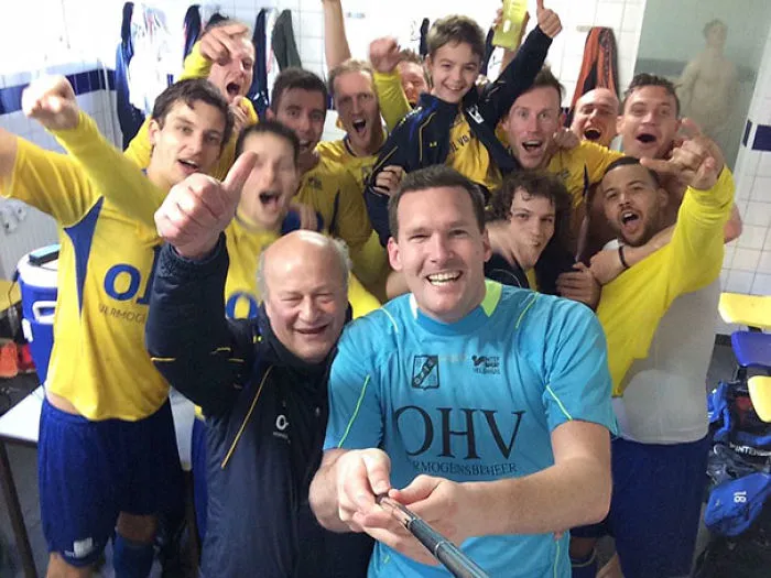 Soccer team celebrating in the locker room, capturing a selfie with excitement and cheers.