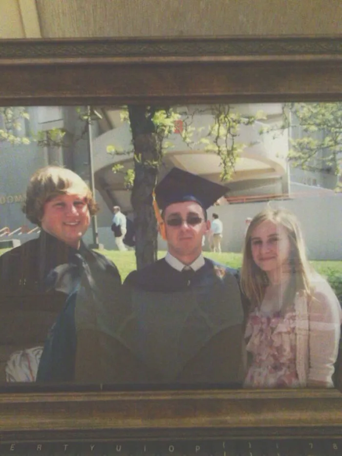 Graduates posing for a photo; unexpected reflection creates illusion for a freaky surprise.