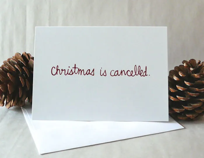 Rude Christmas card with “Christmas is cancelled” text, placed between pinecones.