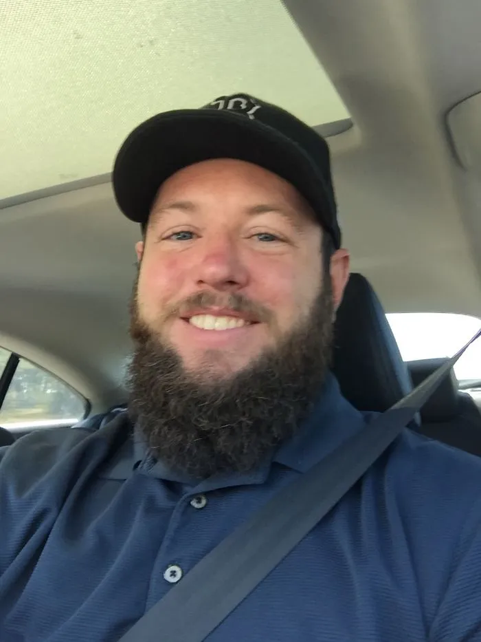 Bearded man in a car, wearing a cap, potentially a real-life doppelganger encounter.