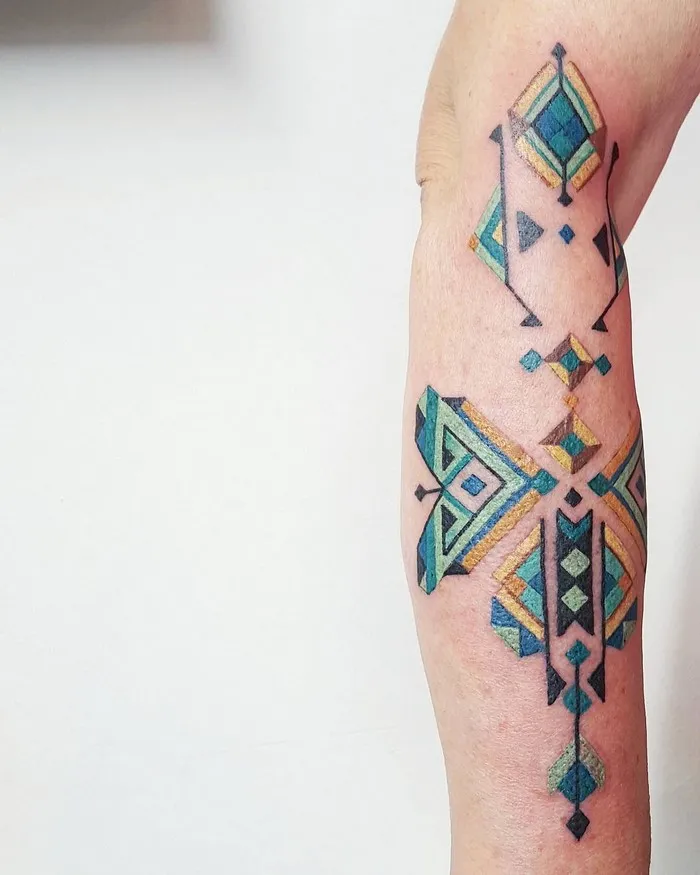Amazonian tribal tattoo by Brazilian artist Brian Gomes, featuring geometric designs in blue and yellow tones.