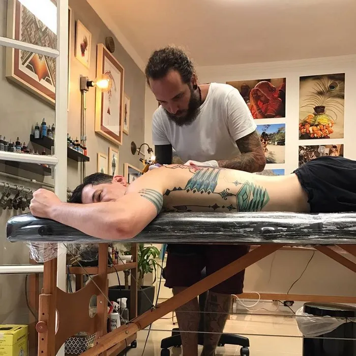 A man getting an Amazonian tribal art tattoo by Brazilian artist in a studio.