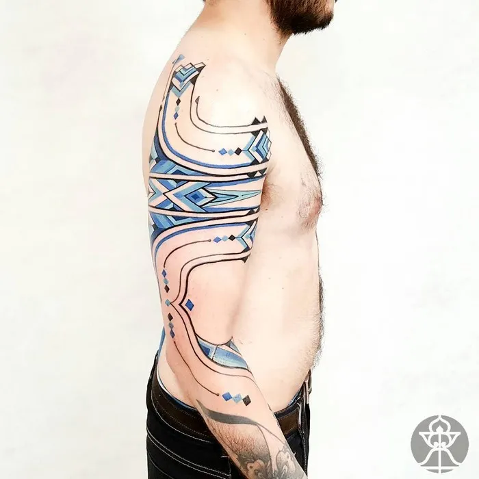 Man showcasing Amazonian tribal art tattoo by Brazilian artist Brian Gomes on his arm and chest.