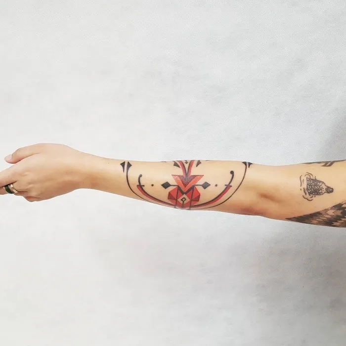 Arm tattoo featuring Amazonian tribal art design by Brazilian artist, emphasizing geometric patterns and bold colors.