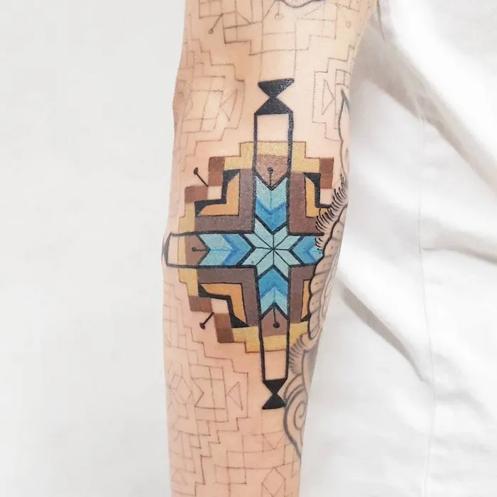 Arm tattoo featuring Amazonian tribal art in blue and brown design by Brazilian artist.