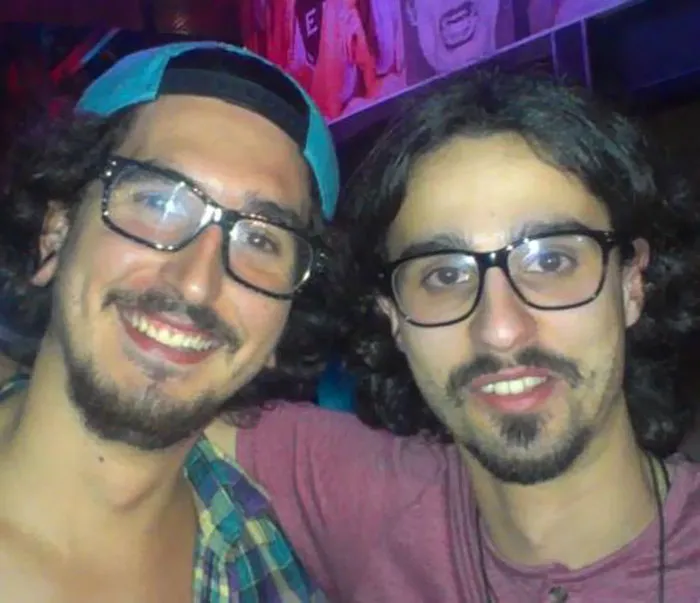 Two men with glasses, resembling real-life doppelgangers, smiling in a casual setting.