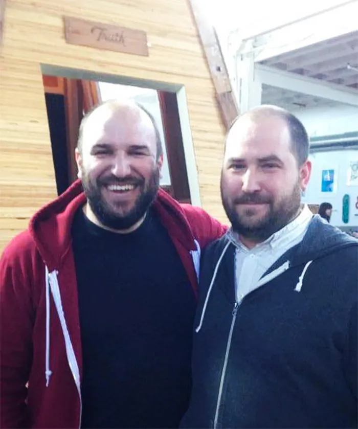 Two men smiling at the camera, both wearing hoodies, illustrating the concept of real-life doppelgangers.