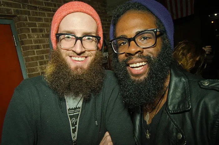 Two strangers with beards and glasses smiling, resembling real-life doppelgangers.