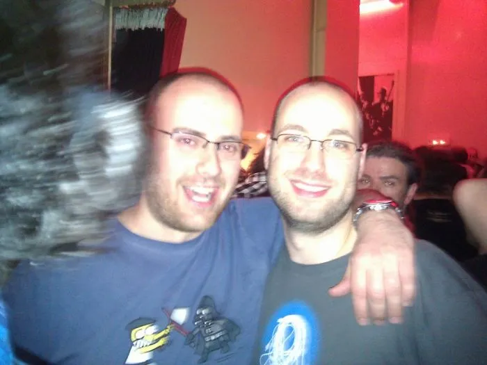 Two men with similar appearances smiling together at a party, embodying the concept of real-life doppelgangers.