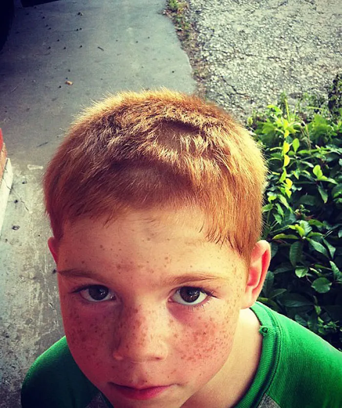 Child with uneven haircut, a self-made decision leading to regret, looking up with a forlorn expression.