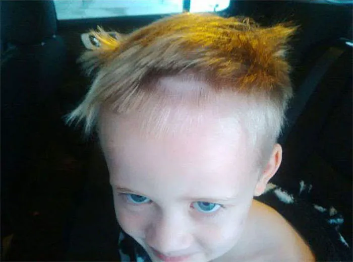 Young child with uneven self-cut hair, smiling despite haircut mishap.